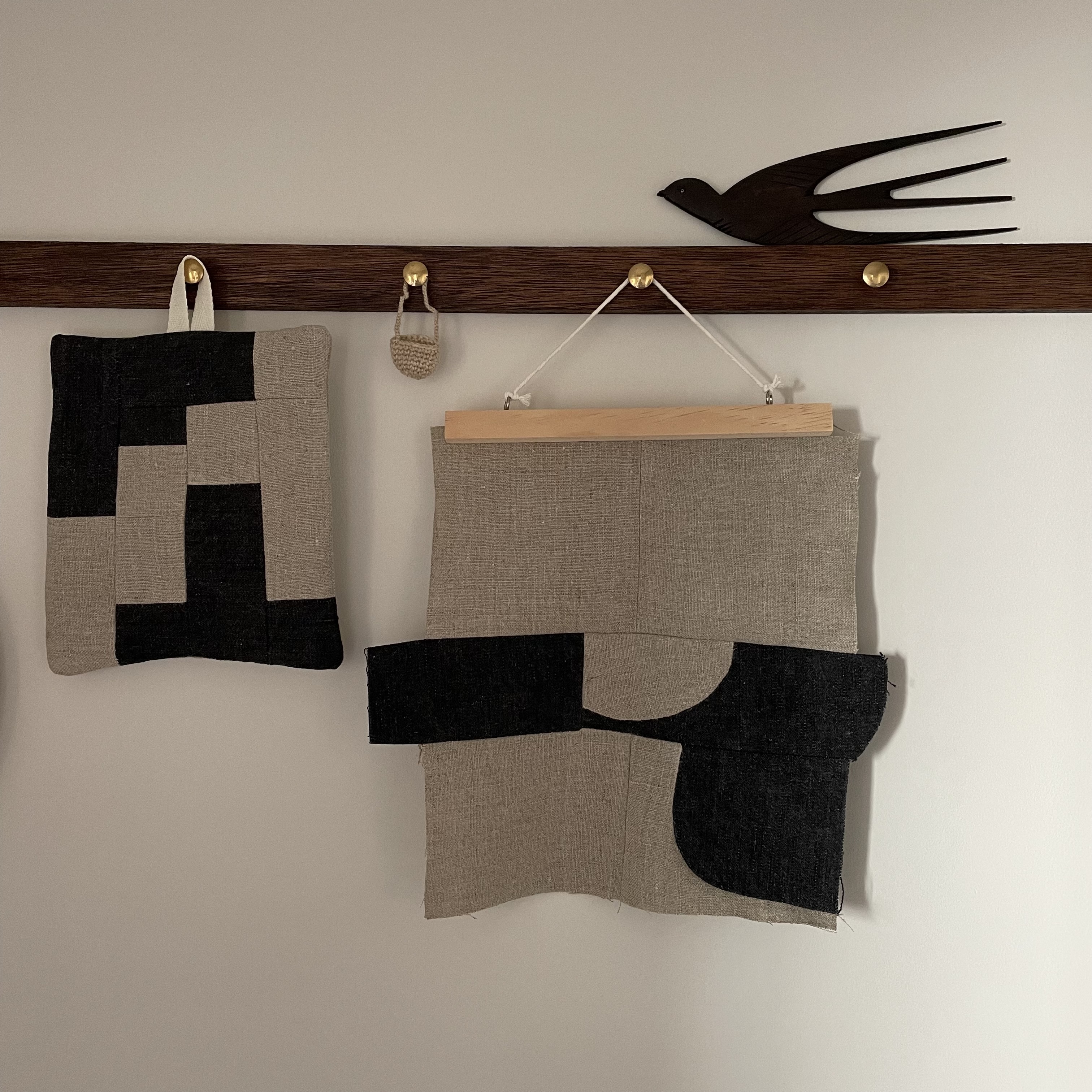 A modern quilted potholder and a vintage wooden swallow wall decoration.