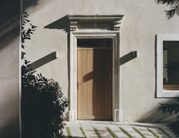 Close-up of the front entrance showing a historic stone arch surrounding a modern minimalist wooden door.