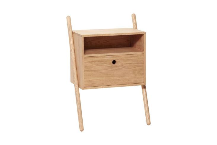 Hubsch Lean Bedside Table in natural oak positioned against a wood-clad wall.