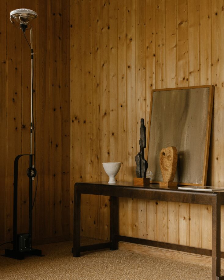 Interior view showing original pine wall cladding, a black floor lamp, and a dark brown birch bench.
