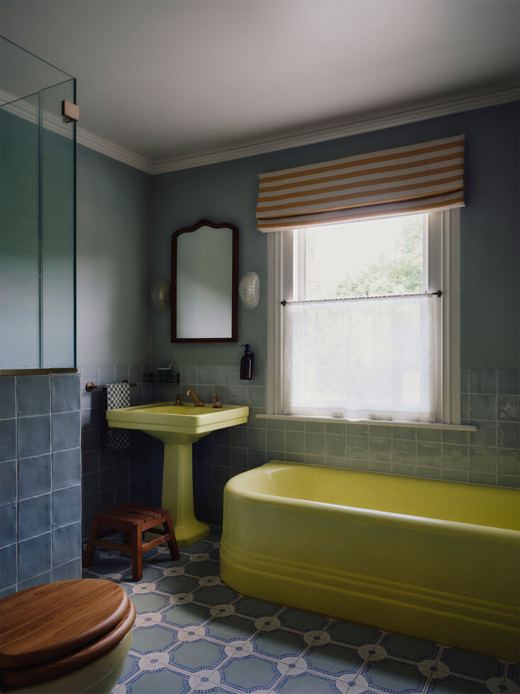 A bathroom with a vintage lemon yellow sink and bathtub, providing a nostalgic and colorful aesthetic.