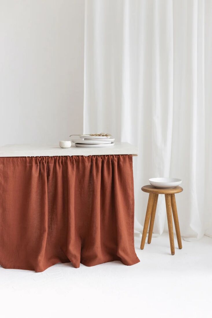 A coral-colored pleated linen skirt covering the base of a table or sink.