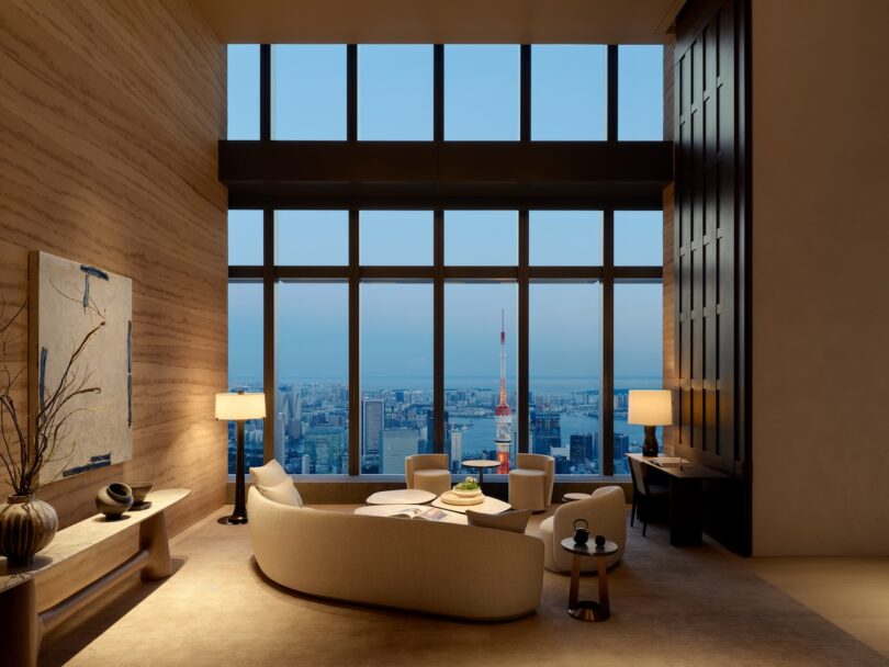 A luxurious living room at night with soft interior lighting and a view of the glowing Tokyo city lights through the window.