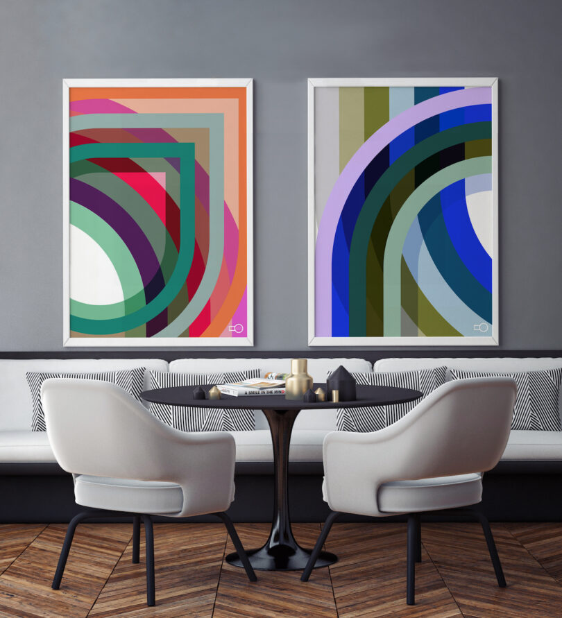 Two framed abstract geometric art pieces hanging in a modern white-walled seating area.