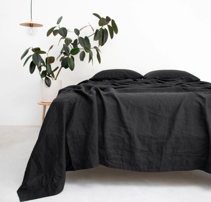 A smooth Noir linen bed blanket from Rough Linen in a dark, moody bedroom setting.