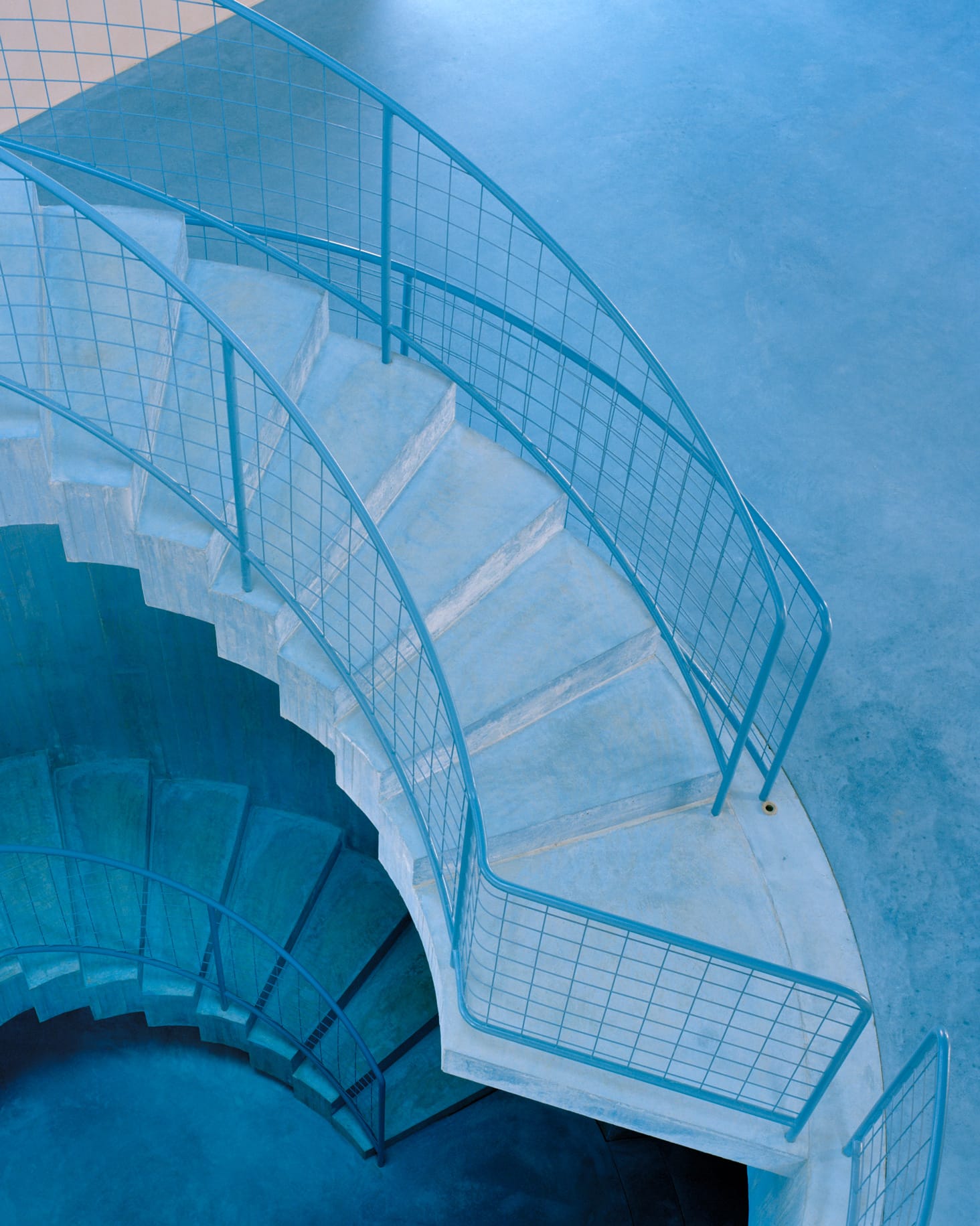 A sculptural blue spiral staircase winding through the levels of the house.