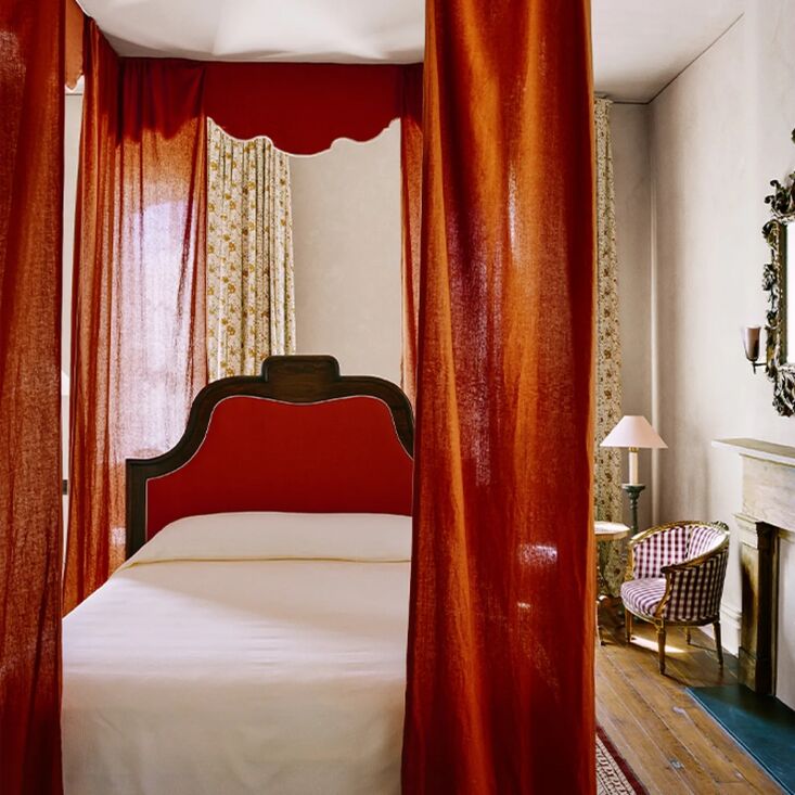 A luxury suite in the Rectory with bold red curtains surrounding a bed.