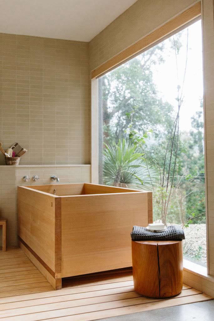 A Japanese-style hinoki wood soaking tub situated in a modern bathroom with garden views.