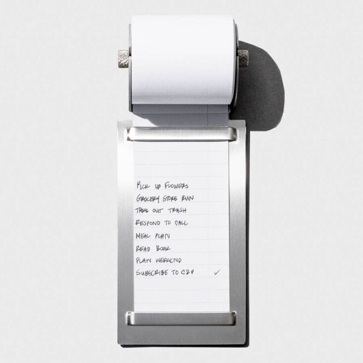 A stainless steel desk task roller with a paper roll for notes.