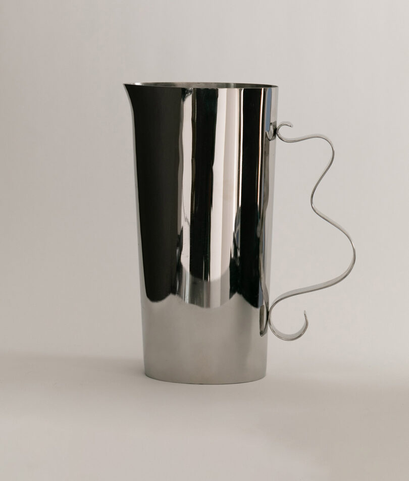 A sleek, mirror-polished metal pitcher with a unique wavy handle design.