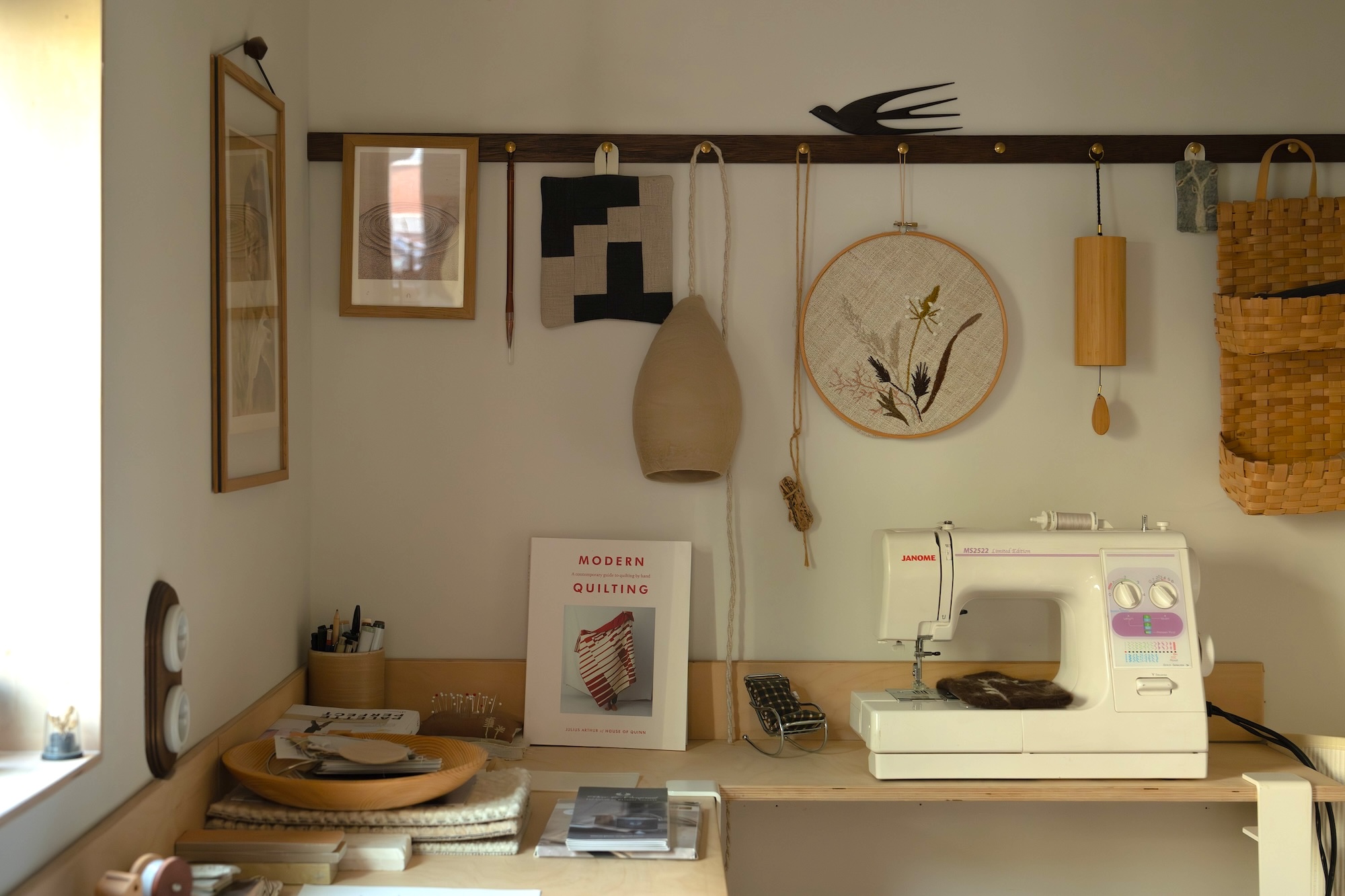 Close-up of an oak peg rail with brass knobs and various items hanging on it.