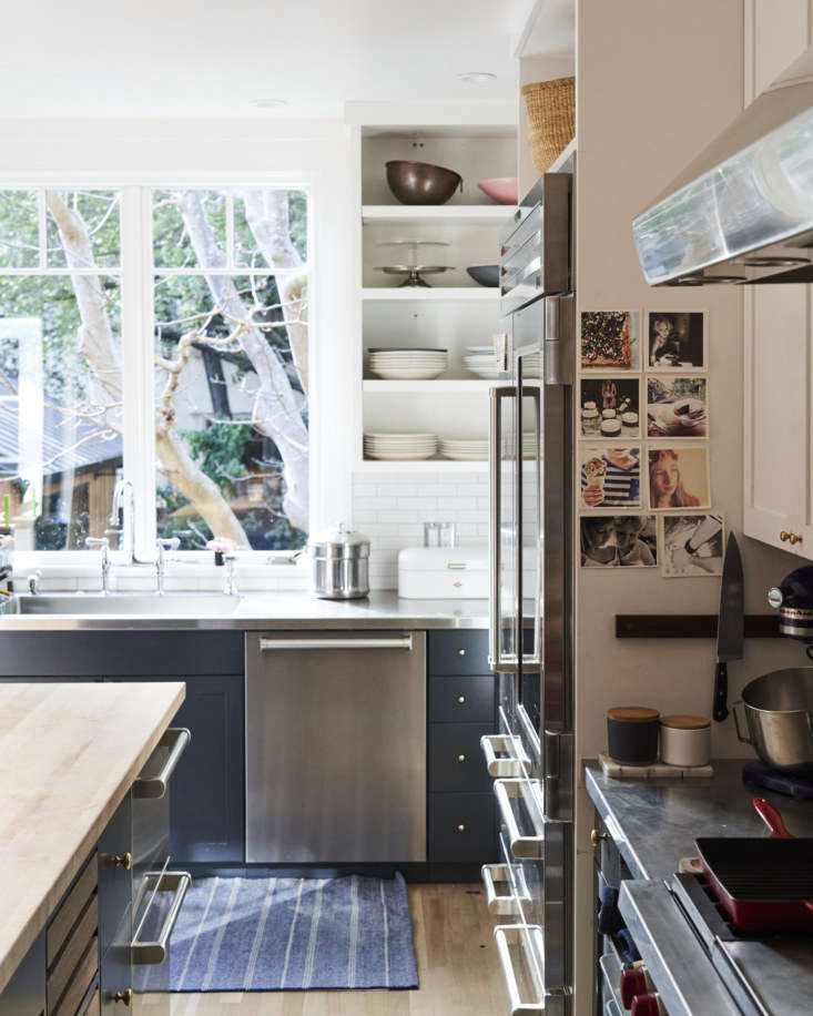 Slatted wood drawers for vegetable storage and a traditional bridge faucet over a sink.