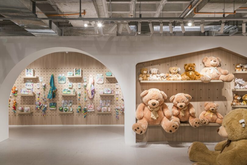 A retail showroom space with wooden pegboard walls displaying plush toys and baby products.