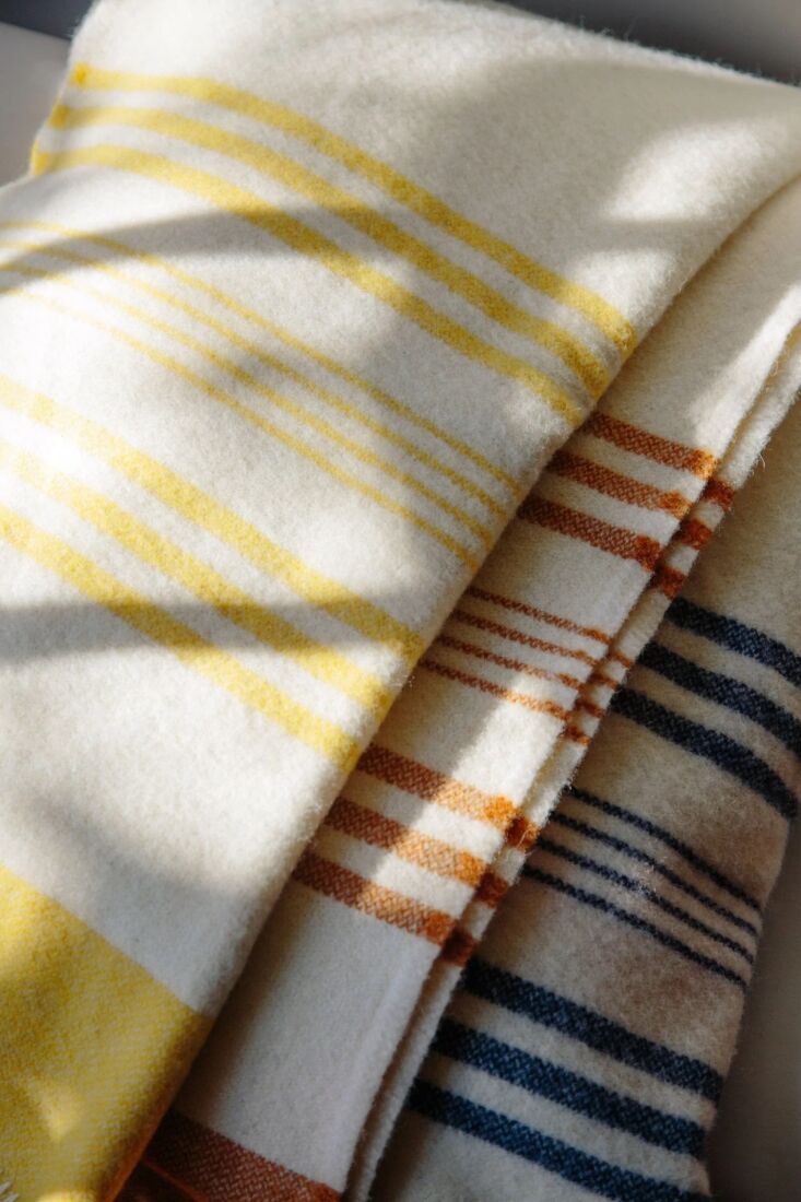 A stack of three colorful lambswool bed blankets by Drove Weavers.