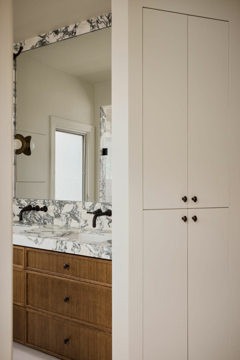 Modern bathroom with a marble countertop, wood vanity, and clean minimalist lines.