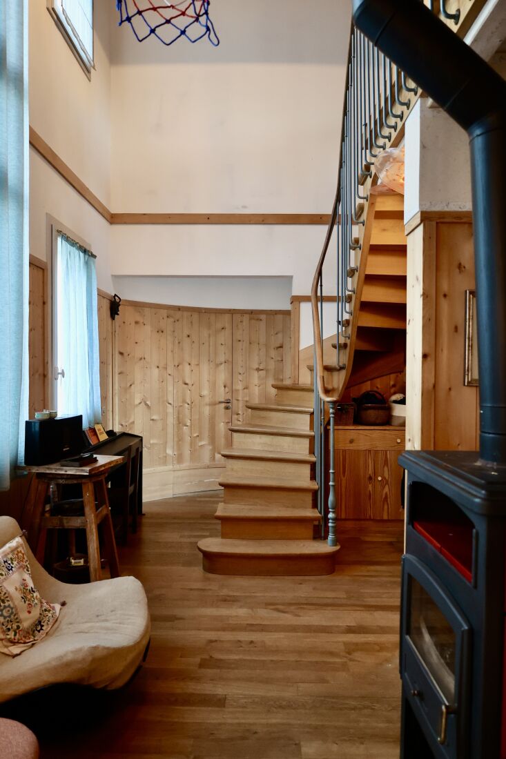 A custom-built winding wooden staircase with iron rails inside the modern duplex.