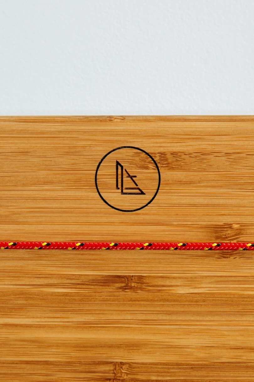 Macro view of a bamboo surface featuring a minimalist logo and a high-strength braided cord.