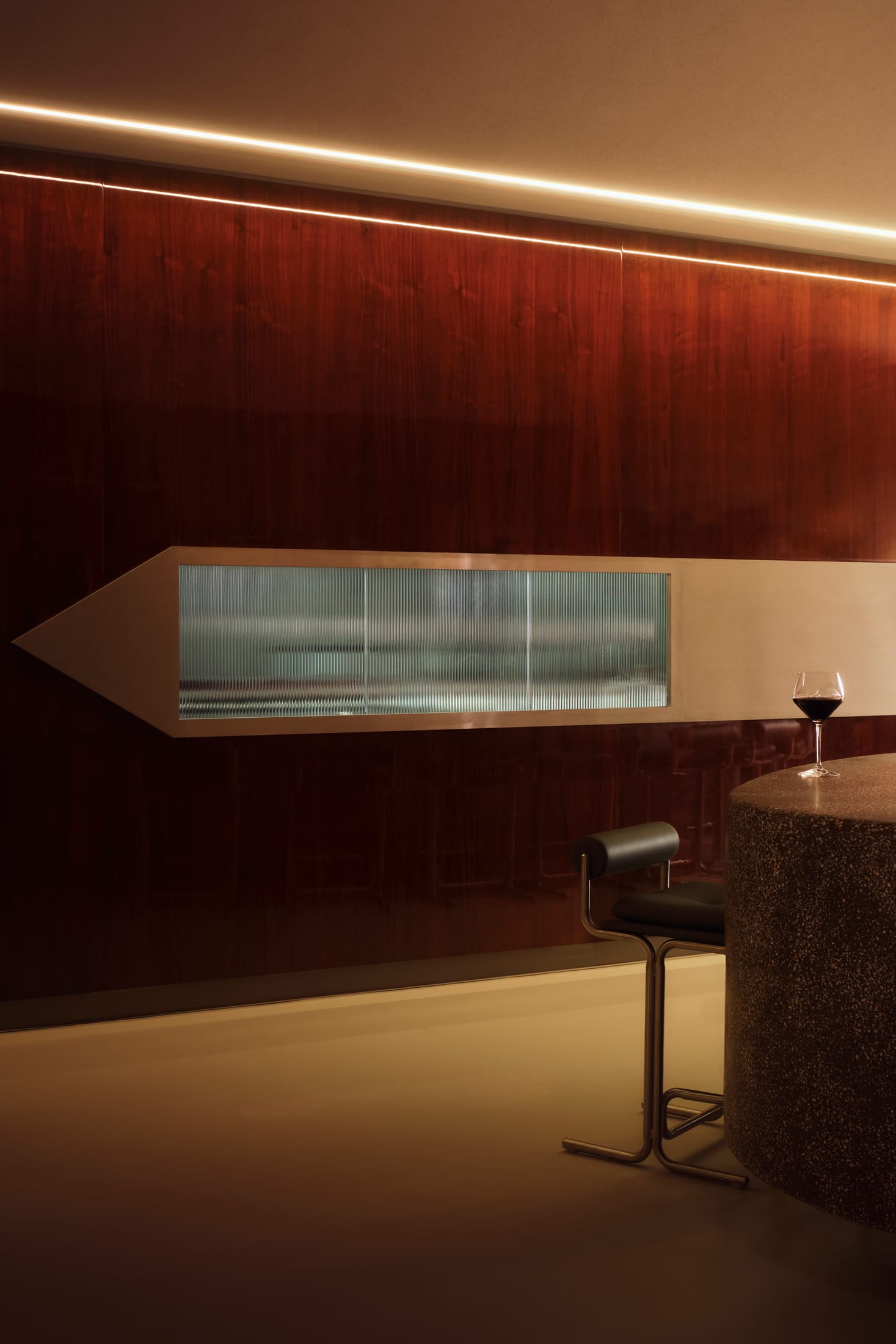 Interior view showing the intersection of light-colored geometric microcement floors and dark architectural pillars.