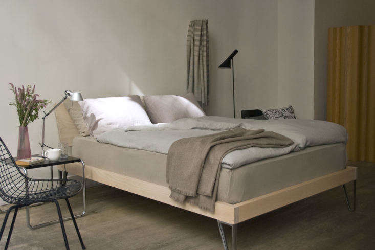 Dual duvets on a wooden bed frame topped with a high-quality alpaca throw.