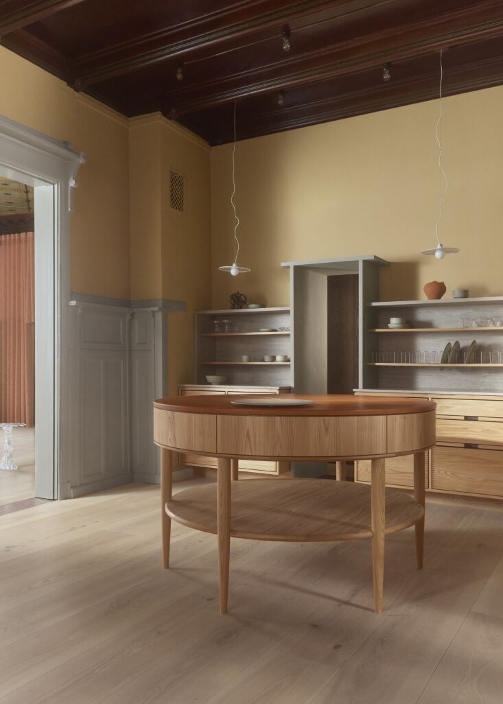Bespoke kitchen island made of Dinesen Douglas wood under a dark high-gloss ceiling with Chipperfield lighting.