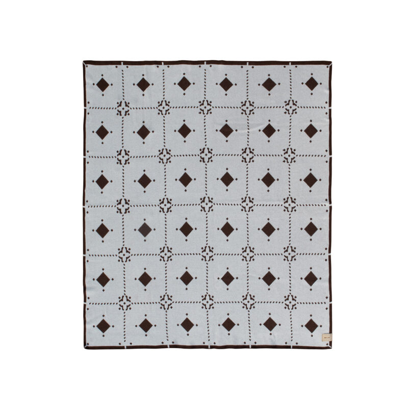 A light gray blanket with a repeating brown diamond pattern and solid brown border.
