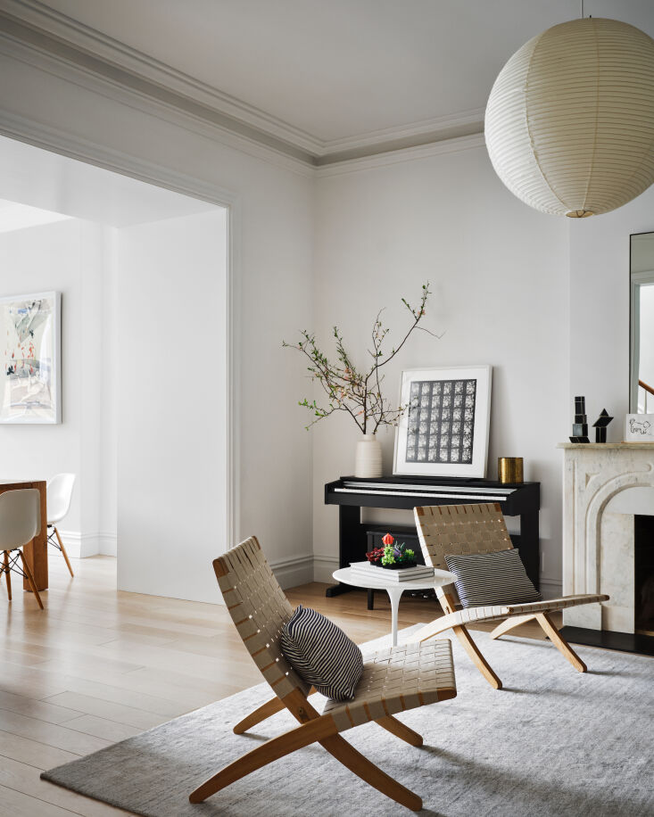Bright minimalist living room with a marble fireplace, mid-century chairs, and a large paper pendant light.