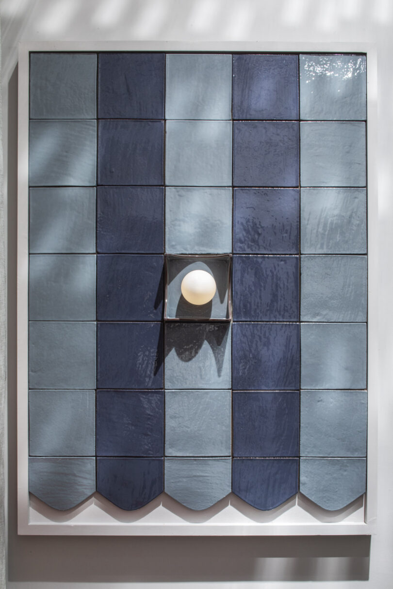 Close-up of a blue ceramic tile grid with a single white spherical light recessed into the center.