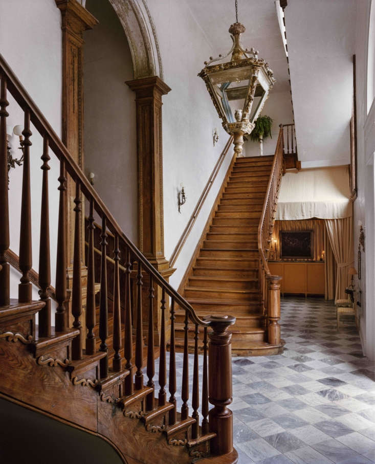 A grand cypress-wood staircase and original plaster walls inside the hotel entrance.