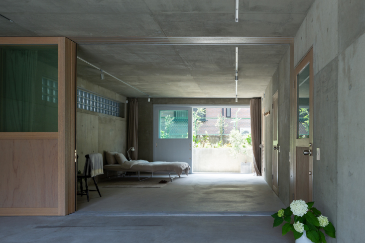 Bright, neutral-toned bedroom in Tokyo featuring concrete walls and light wood accents.
