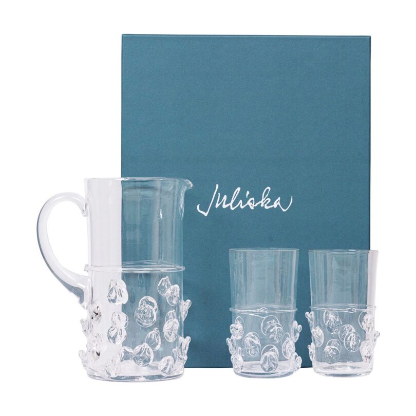 Two clear water glasses and a pitcher on a table next to a blue box.