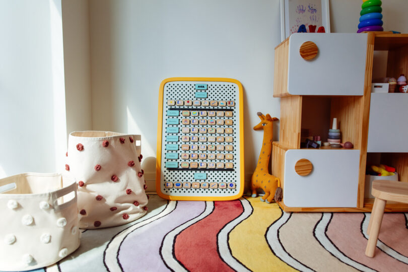 A bright, organized children's room with a wavy rug, toy giraffe, and modern wooden storage unit.