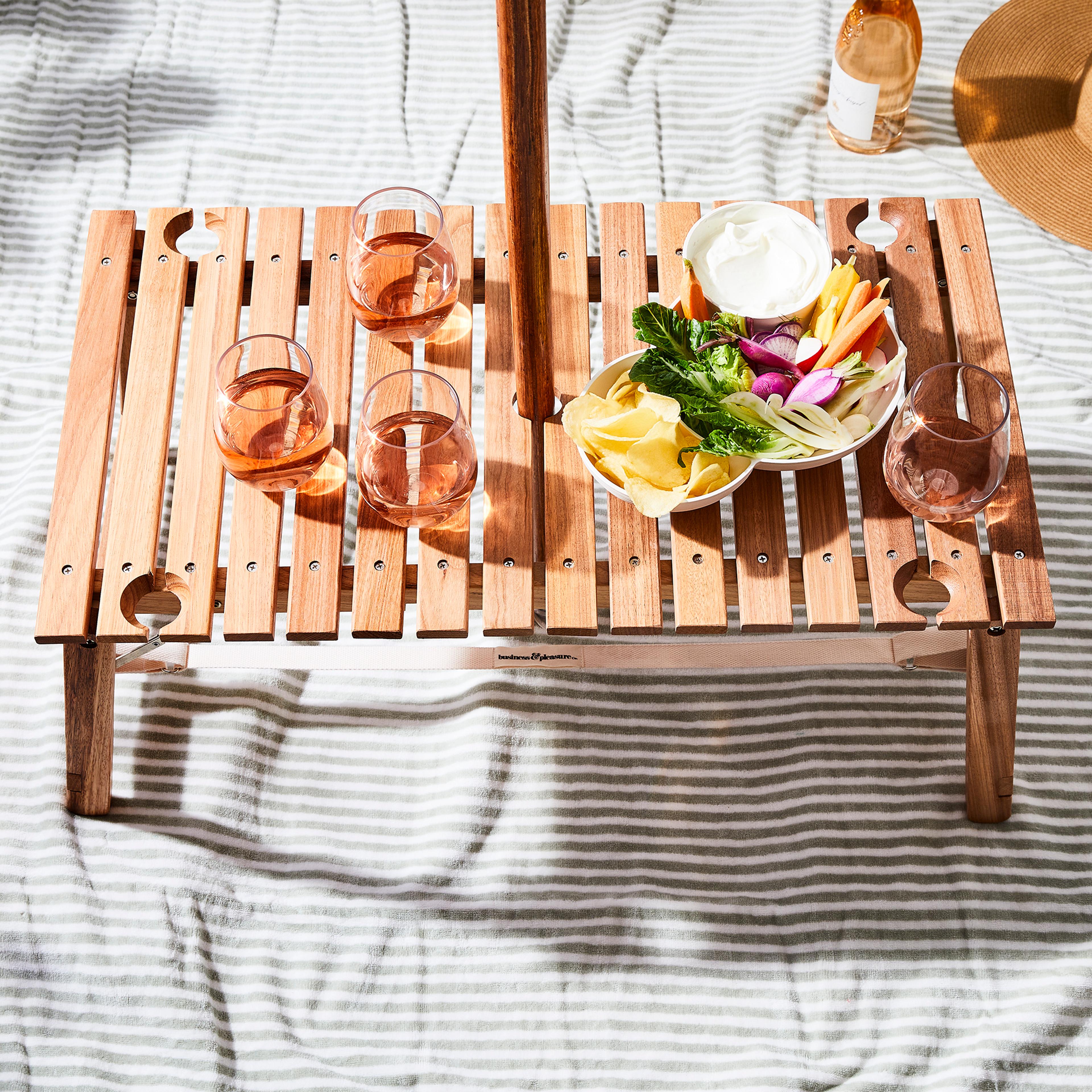 A portable roll-up wooden picnic table set up on the grass.