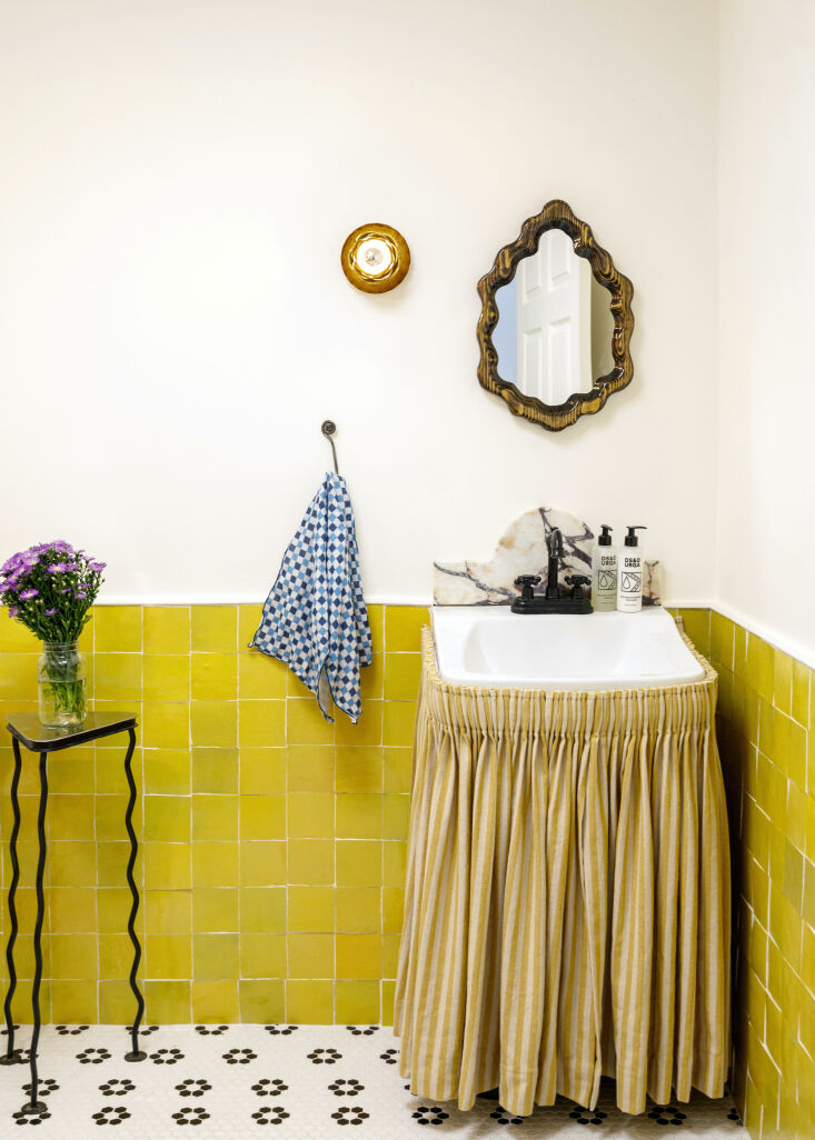 A chartreuse sink skirt paired with matching lemony zellige tiles in a bright studio bathroom.