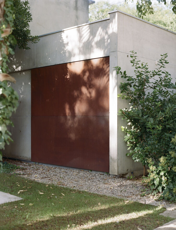 A modern outbuilding door constructed from rusted Corten steel.