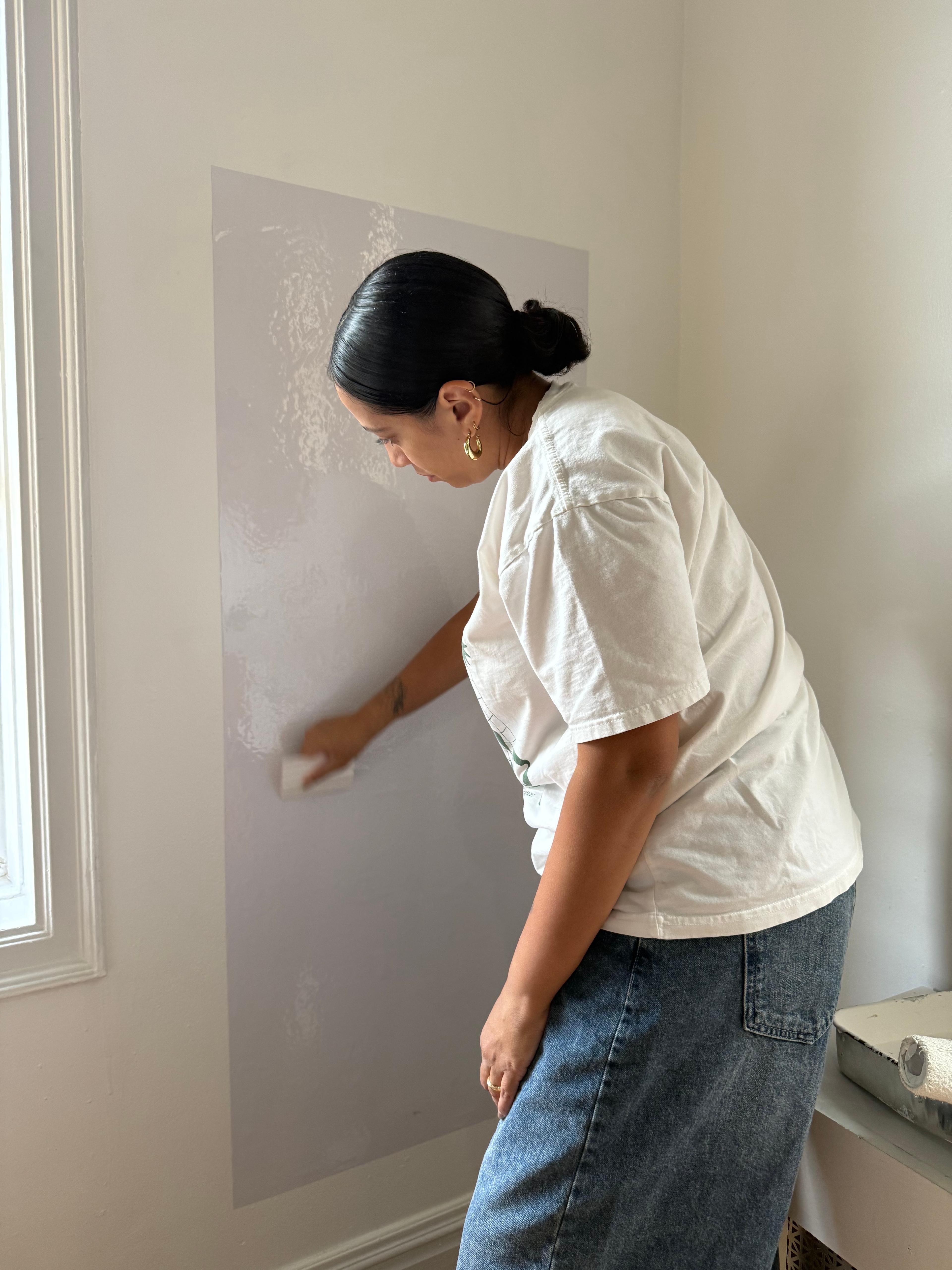 A decorative wall decal being applied to the wall behind the art station area.