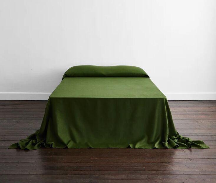 An Olive-colored Heavy Linen Bed Cover from Bed Threads draping elegantly toward the floor.
