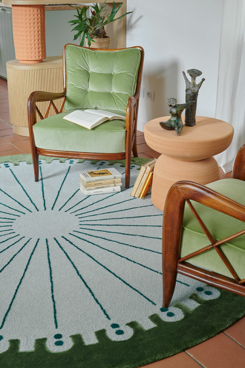 Mid-century modern living room with green velvet chairs and a patterned rug.