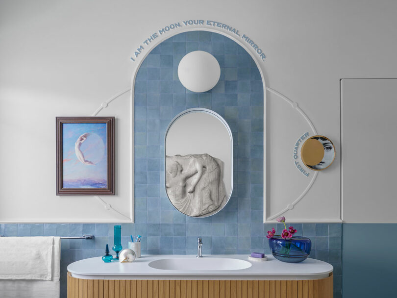 Bathroom featuring a blue tiled arch, oval mirror, and poetic text on the wall.