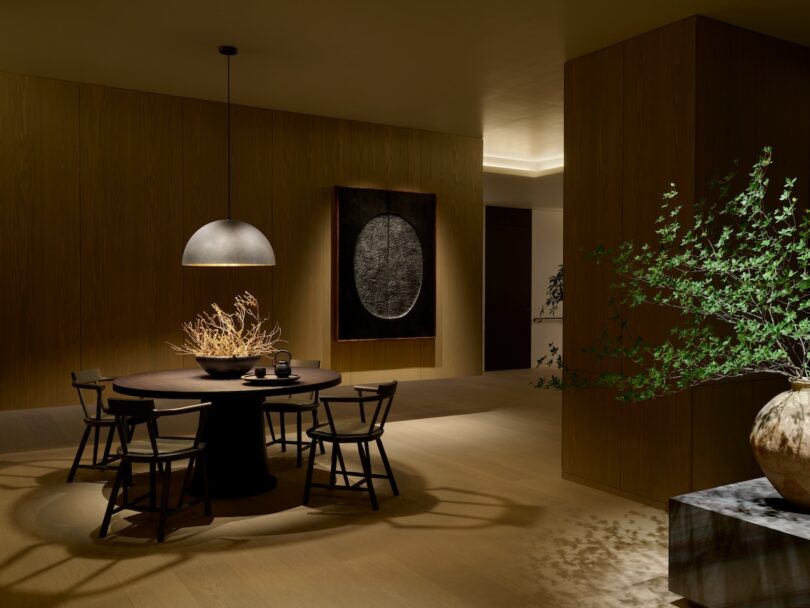A modern dining room with a round table, minimalist pendant lighting, and organic decorative elements.