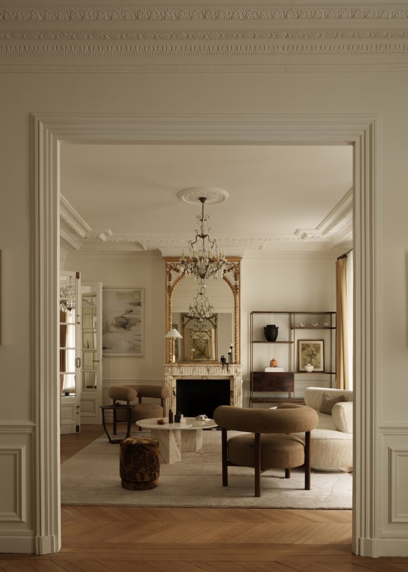 Sophisticated Haussmannian living room with tall mirrors, wall moldings, and a marble fireplace.