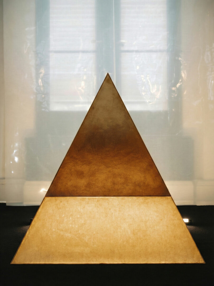 Minimalist triangular sculpture with metallic surfaces and ambient lighting.