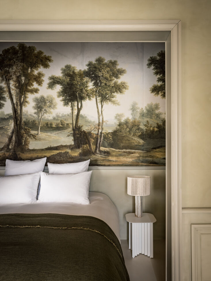 A bed alcove framed by a wallpaper mural and soft lighting.