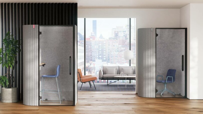 Interior of a soundproof pod featuring textured gray acoustic walls and blue seating overlooking a city view.