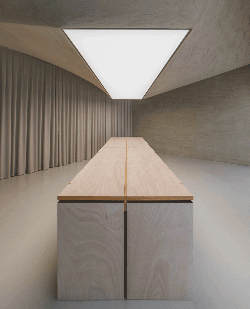 Architectural shot looking up at the twisting ceiling structure and central skylight of the workshop.