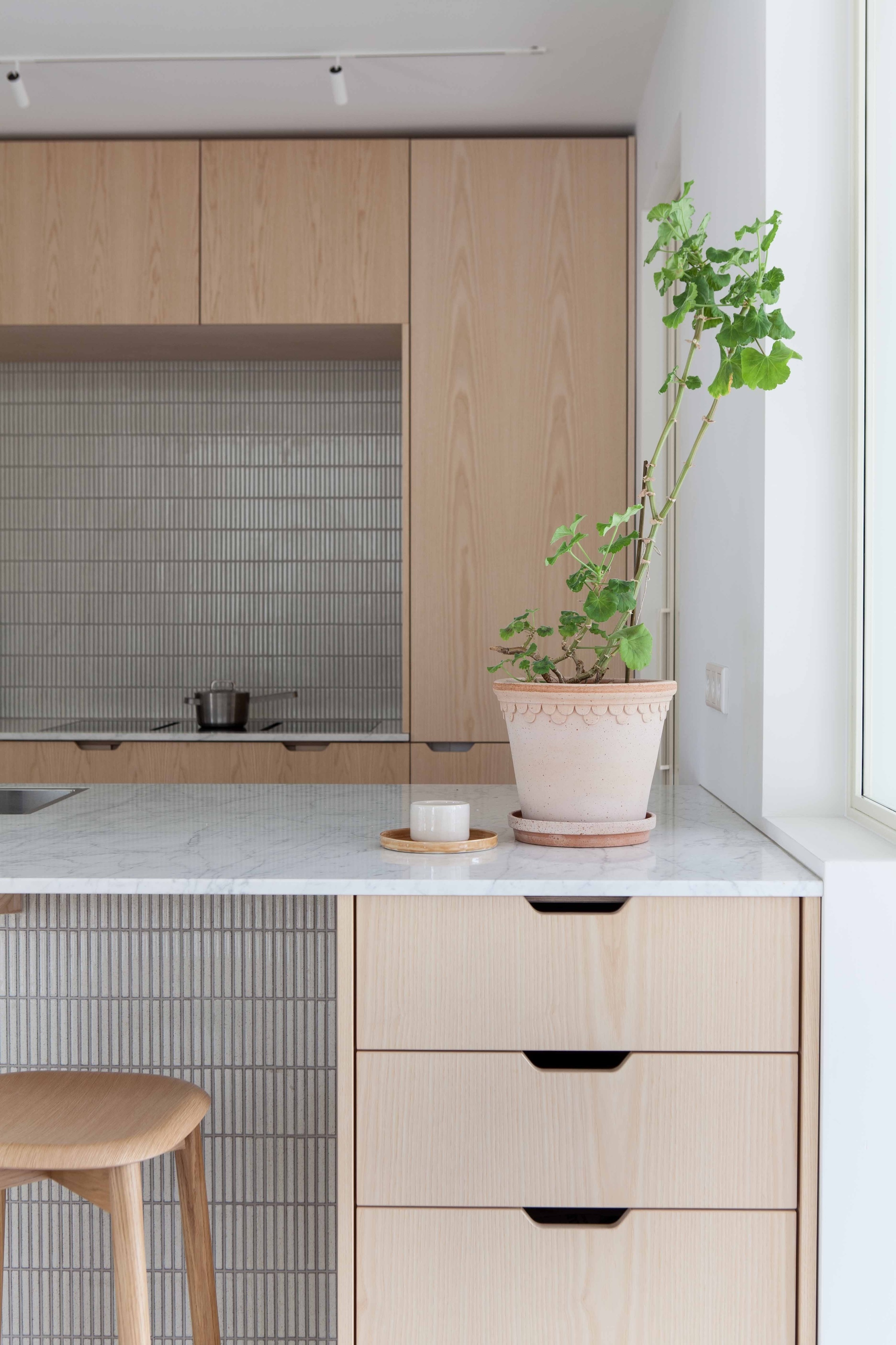 Custom ash-paneled kitchen cabinetry with integrated appliances and marble countertops.