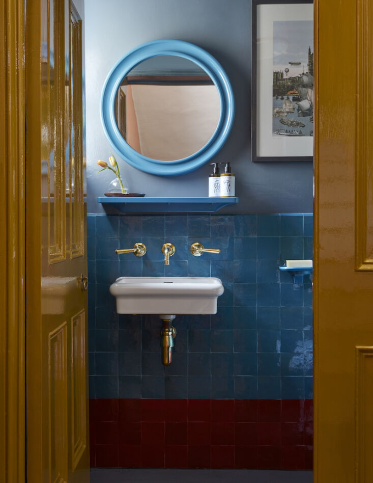 Bold powder room with indigo walls, turquoise tiles, and blue Bakelite accessories.