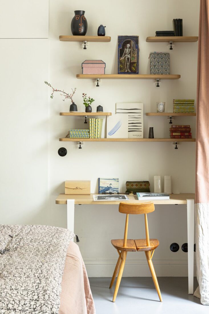 A small bedroom corner utilized as a workspace with a wall-mounted desk and floating shelves.