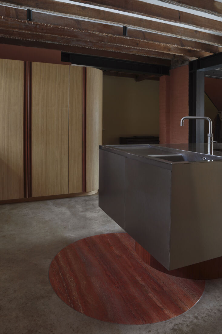 Circular red travertine insert in a concrete floor covering old plumbing work.