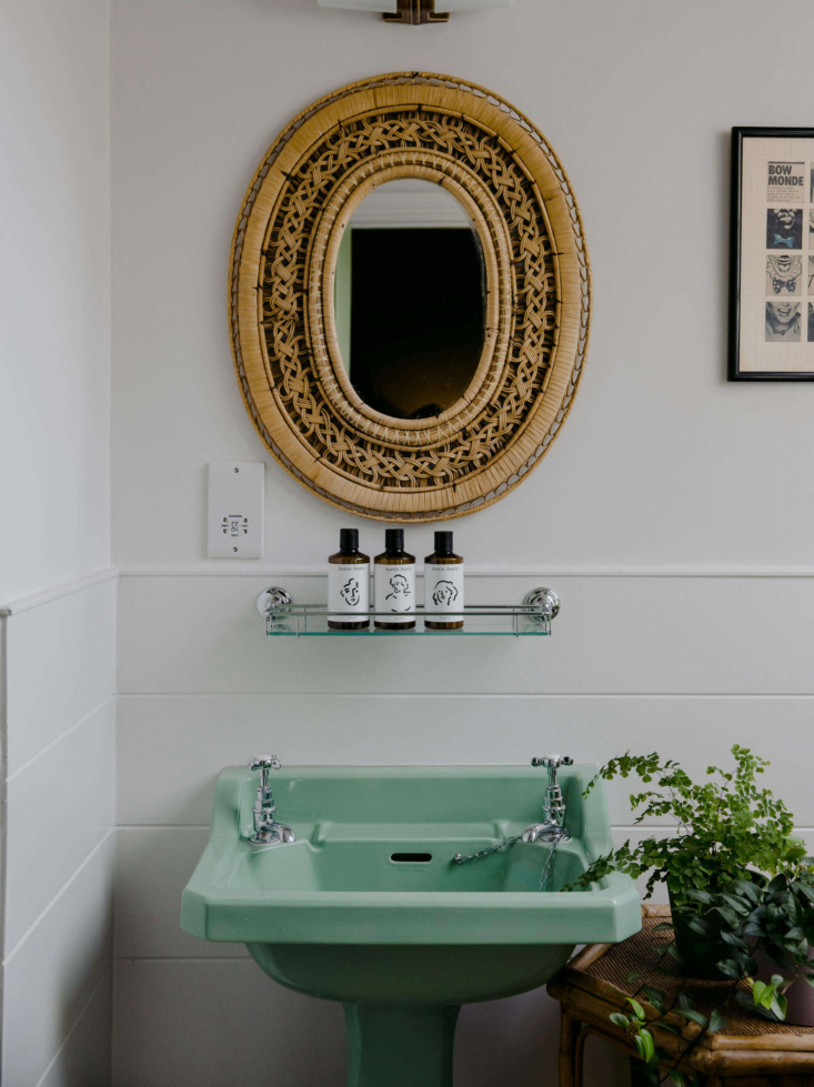 Retro bathroom with a mint green vintage pedestal sink and glossy tiles.