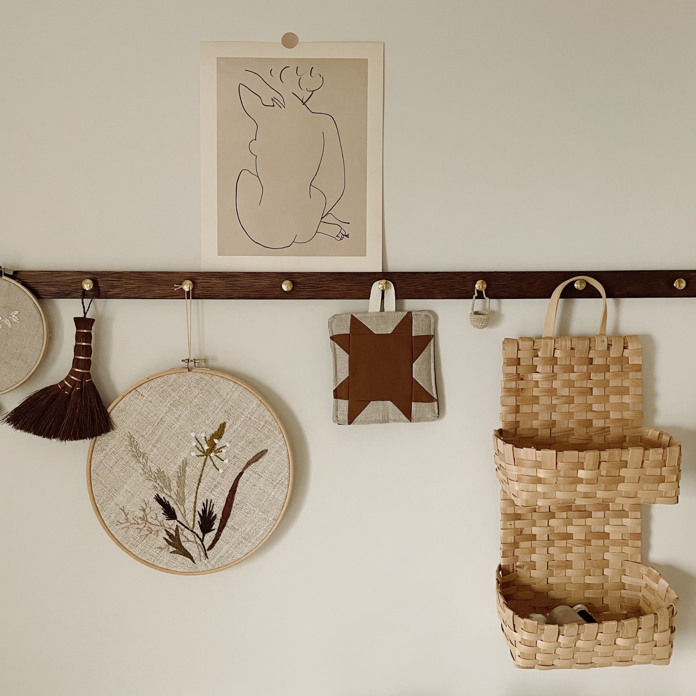 A tiered wire hanging basket containing craft materials and embroidery work.